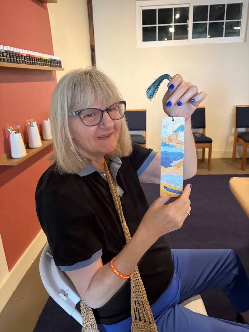 A member shows off a hand-painted bookmark made in arts and crafts