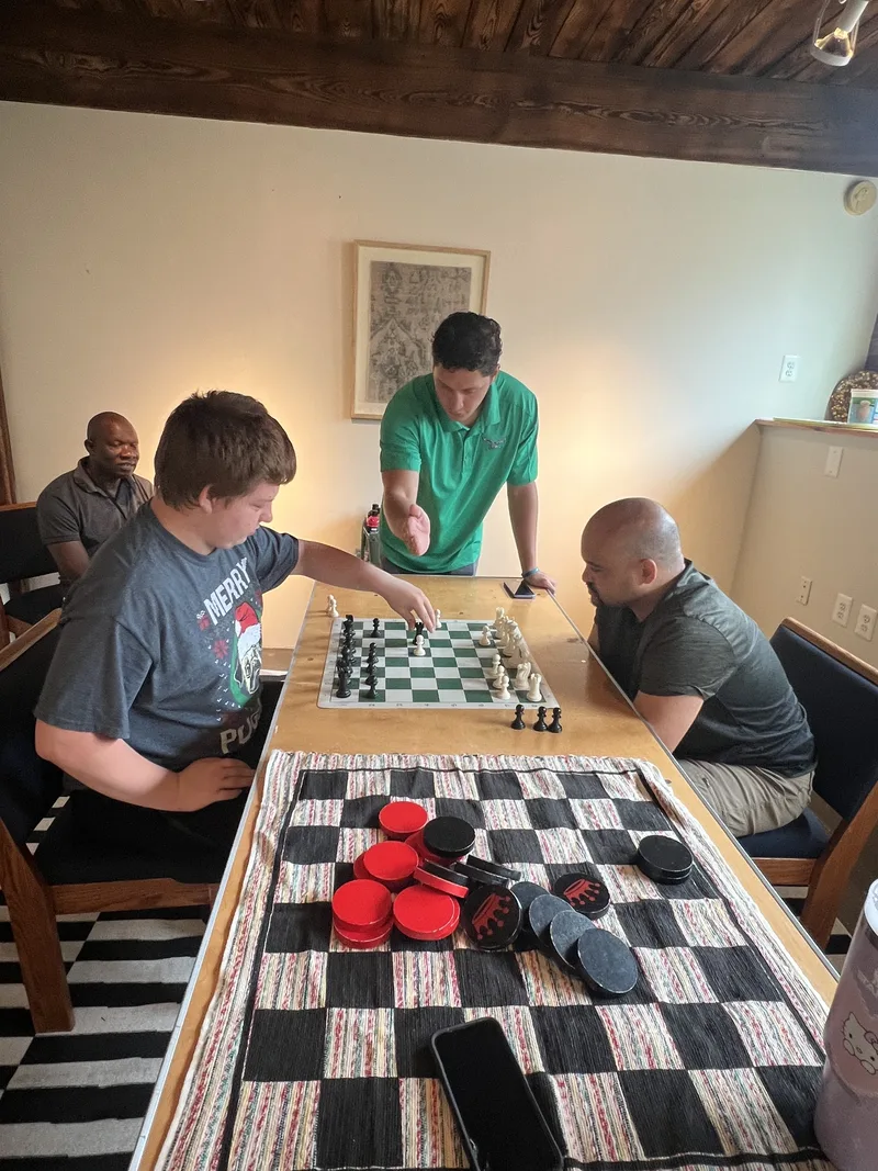 Members study the board mid-match at Chess and Checkers Club