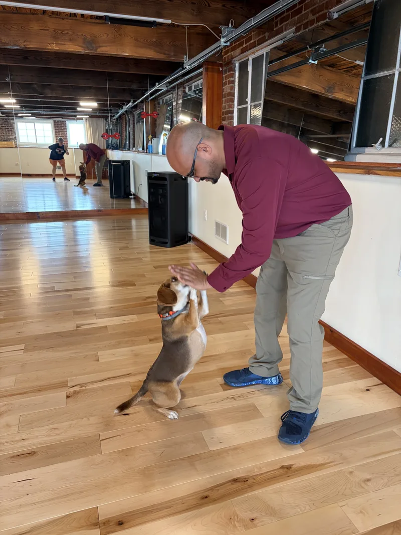 A member reaches down to greet Coco Bean, the Clubhouse mascot