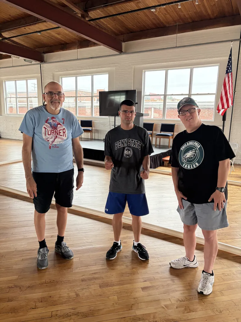 Three friends in their favorite team shirts pose together in the gym