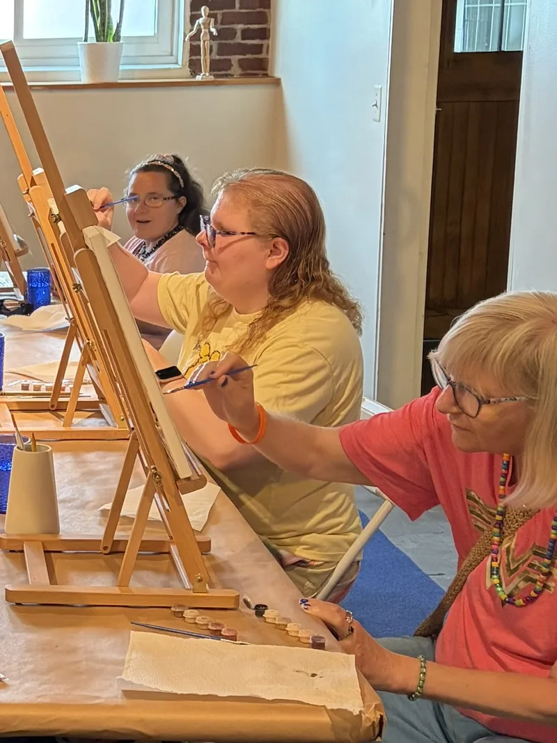 Members paint at easels side by side during a Paint by Numbers class