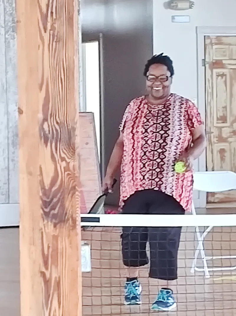 A member smiles mid-game at the pickleball net